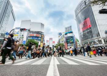 Crowd of People during rush hour walking over zebra crossing at Shibuya Station in Downtown Tokyo. Motion Blurred People. Tokyo, Japan.