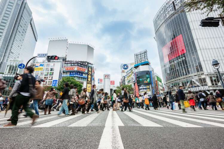 Crowd of People during rush hour walking over zebra crossing at Shibuya Station in Downtown Tokyo. Motion Blurred People. Tokyo, Japan.