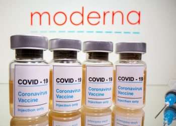 FILE PHOTO: Vials with a sticker reading, "COVID-19 / Coronavirus vaccine / Injection only" and a medical syringe are seen in front of a displayed Moderna logo in this illustration taken October 31, 2020. REUTERS/Dado Ruvic