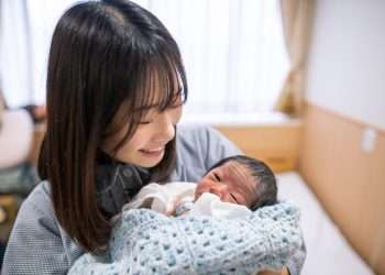 Young mother holding her new born baby in hospital