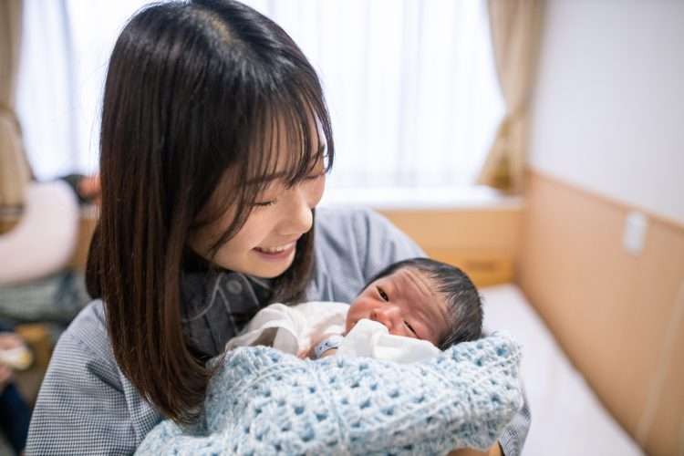 Young mother holding her new born baby in hospital